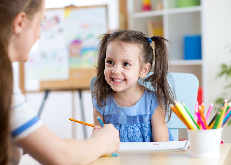Clinician working with a smiling girl at a therapy table