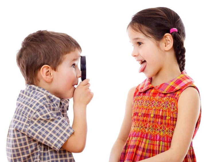 Boy making a quiet gesture toward a girl with open mouth