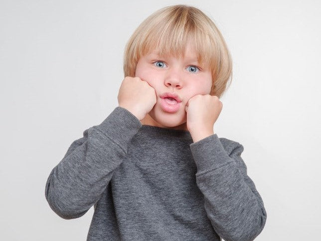Boy pressing his fists against his cheeks