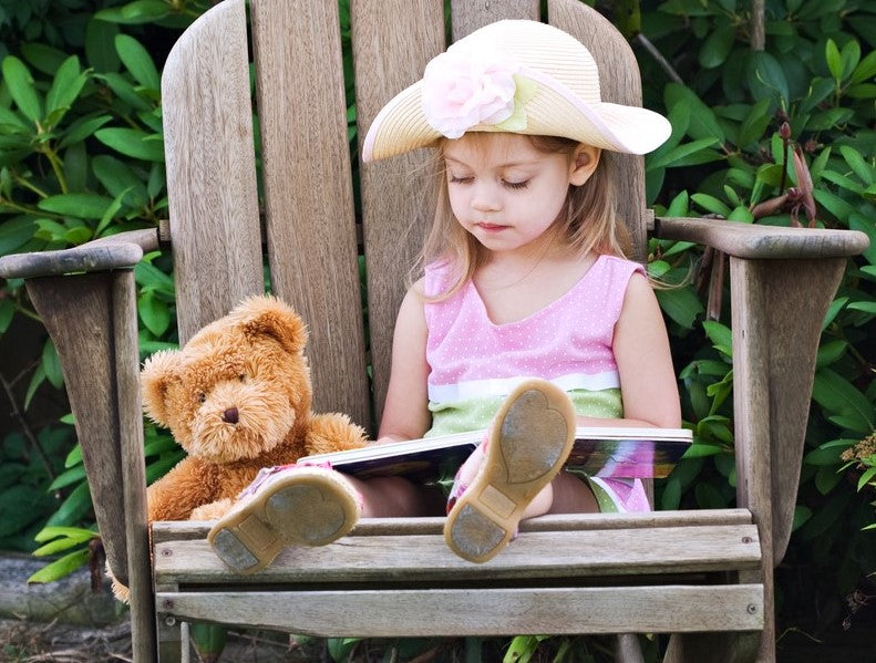 Girl reading a book with a teddy bear