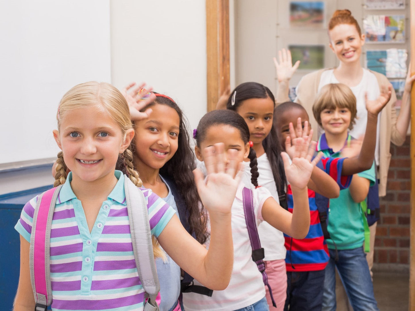 School children waving with a teacher
