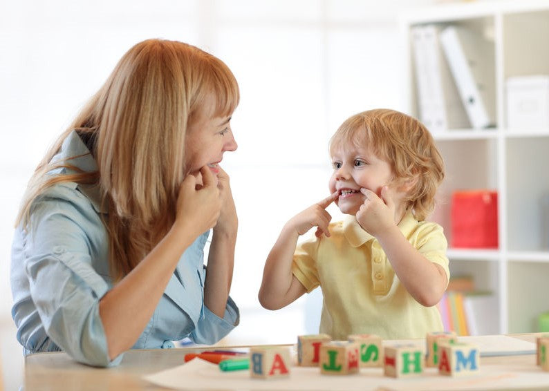 Clinician and child smiling during a therapy activity