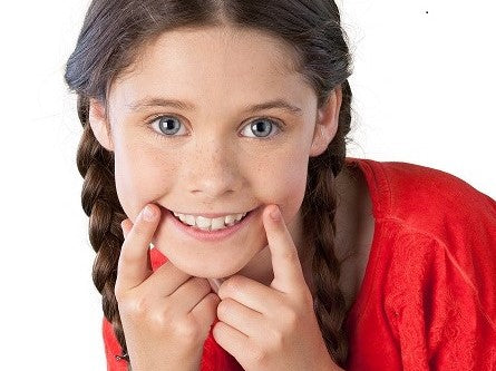 Smiling girl in a red shirt touching her mouth
