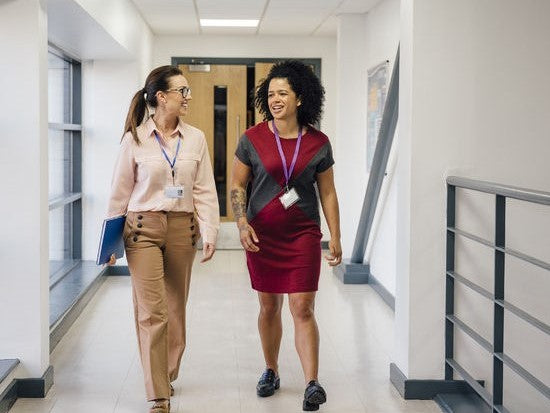 Two teachers talking while walking in a hallway