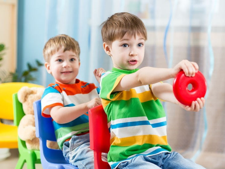 Two boys playing with toy steering wheels